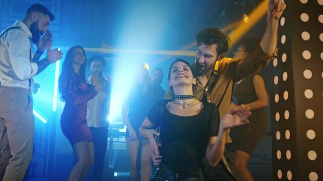 Young couple at the bar dancing together with friends all having a great time