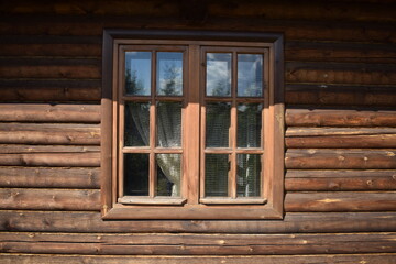 Closed window of a wooden house in the north of Russia on a sunny day.