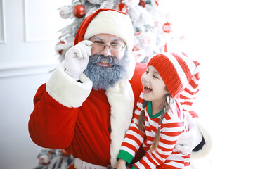 Santa Claus sitting with little cute elves over Christmas background. Time of miracles. Gifts from Santa Claus.