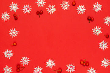 Xmas wreath. White snowflakes, red berry in Christmas composition on red background for greeting card. Flat lay, top view, copy space.