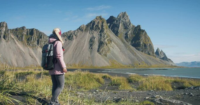 Women enjoying costline with black sand beach in Stokksnes and Vestrahorn mountain in the background