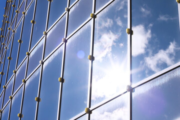 Architectural detail of the facade with multiple reflections of other buildings and the sun. Modern building. Architecture background