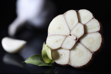 Fresh garlic clove on black background. Garlic is rich in vitamins, useful spring, good spices. Garlic sliced on a dark background. Raw sliced garlic.