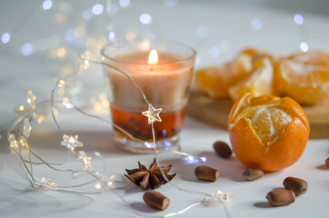 Tangerines, candle, spice and garland on a blurred background.