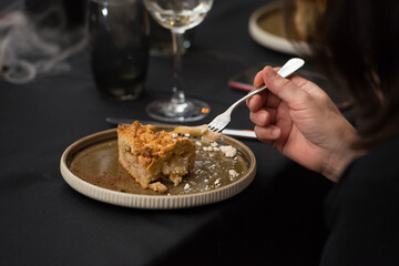 Delicious apple pie charlotte with caramel on the plate on black tablecloth