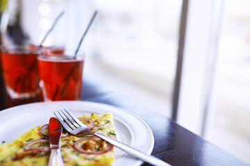 A glass of drink tropical fruits soda and seafood pizza on wooden table in the cafe.