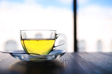 Hot steaming green tea in a cup on a rustic background