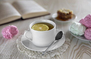 Breakfast with red currant marshmallows and light green Apple with lemon tea. White tea Cup on a white background open book honey.