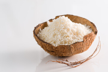 Coconut flakes in coconut shell on white background side view