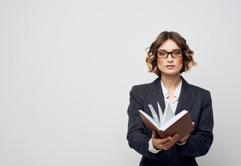 Business woman with a book in her hands on a light background classic suit fashionable hairstyle Copy Space