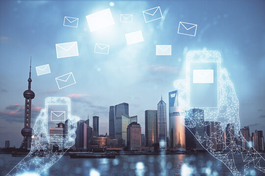 Double exposure of envelop hologram flying from gadget and city view background. Concept e-mail.