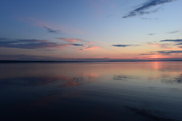 Fototapeta premium Twilight glow in the clear sky on the horizon above the calm water surface