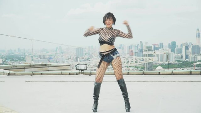 Young Asian sexy woman dancer practicing to dance on rooftop over cityscape background . artist dancing on skyscraper performance k-pop girl group