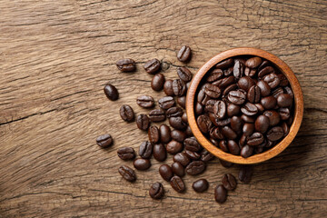 Flat lay (top view) of Roasted coffee beans in wooden bowl on wood background.