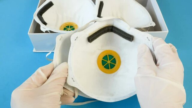 Hand in medical gloves packing many different respirators with high protection level 3M, ffp2 and ffp3/N95. Protection against coronavirus. Respritors production, packing and delivery.