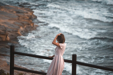 A girl in a romantic dress walks alone near the sea. Waves and windy weather