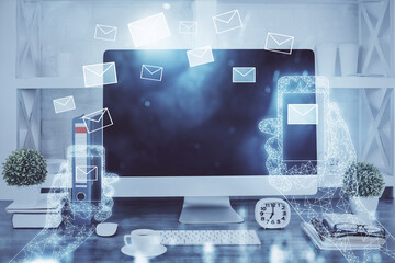 Desktop computer background in office and flying envelops hologram drawing. Double exposure. Electronic mail concept.