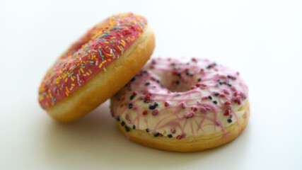 Close up of two delicious sweet tasty colorful donuts glazed and sprinkles isolated on white background