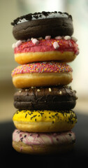 View of assortment colorful frosted delicious tasty stacked doughnuts. Colored sprinkle glazed donuts with marshmallow and chocolate
