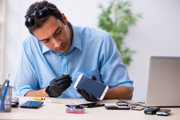Young male technician repairing mobile phone