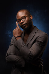 Close up portrait of young african man isolated on black studio background.Photoshoot of real emotions of male model. The man adjusts his glasses.