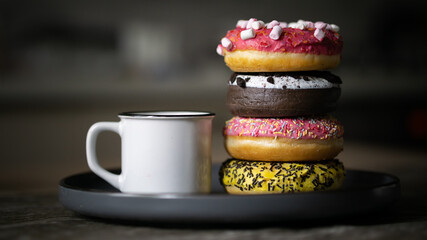 Close of cup of coffee cup with different flavour glazed sprinkled stacked donuts blank white