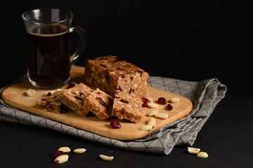 Homemade Toffee or sherbet, traditional Oriental sweet made from milk and sugar with nuts and dried cranberries. Dessert from Arabic or Turkish cuisine on wooden cutting board on black background