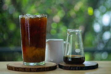 A glass of cold coffee and ice served with cream in small jar.