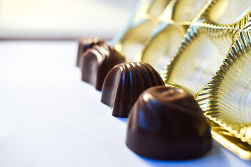 Chocolate candies next to a box on a white background