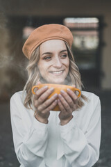 Happy young woman holding cup of steaming tea