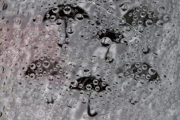 Rain. Raindrops fall down against the gray and white background with black umbrella silhouettes. Abstract fantasy.