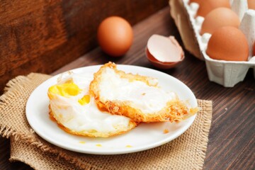 Hot fried eggs and fresh eggs on the wooden table