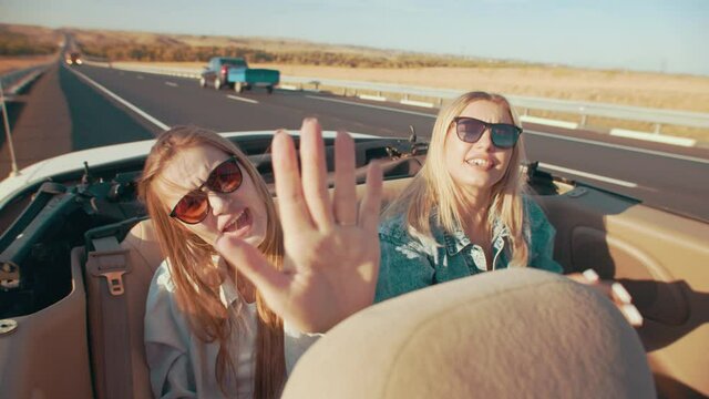 Friends have fun and sing in the car. Two women in a cabriolet, going on vacation on a summer day.
