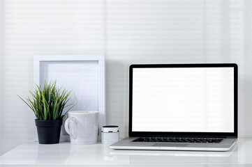 Mockup blank screen laptop on white top table in modern office room with shadow on the wall.
