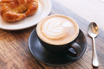 Coffee and croissant on wooden table, top view .