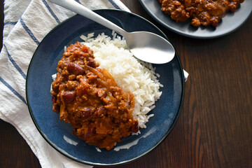 Chilli con carne with rice on a blue plate.  Traditional Mexican food.  Copy space is on the right side. 