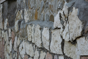 Background of flat stones and cement, decorative wall made of natural materials. Stony hard surface made of parts of different sizes and shapes with a sandy tint