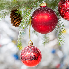 Bright red Christmas balls on a spruce branch with a pine cone. Christmas and New Year concept