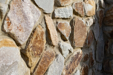 Background of flat stones and cement, decorative wall made of natural materials. Stony hard surface made of parts of different sizes and shapes with a sandy tint