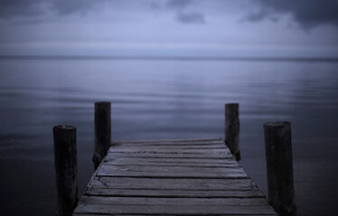 cloudy landscape, on the horizon of the sea and sky an old wooden bridge for fishermen and small boats. Melancholic mood and calmness. minimalism in nature. calm water and sky