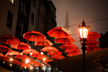 Pedestrian street in the center of Novi Sad decorated with red umbrellas overlooking the ancient cathedral night cityscape
