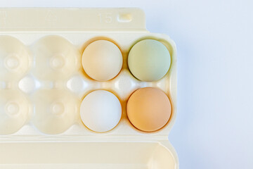 Multicolored chicken eggs lie in foam containers for storage and carrying on a light background. Close up. Soft focus