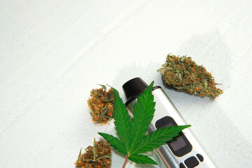portable electronic vaporizer for smoking dry herbs next to hemp leaves