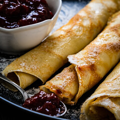 Sweet crepes with strawberries  jam on wooden table
