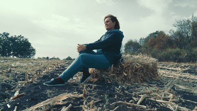 Mature Woman on a haystack. Women farmer sist on a haystack in land.
