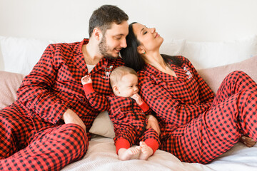 Happy family in red pajamas on the bed