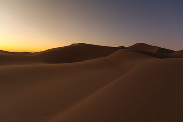 Fototapeta na wymiar Dreamy desert concept at Twilight of dawn at desert dune of Erg Chigaga, at the gates of the Sahara. Morocco. Concept of travel and adventure