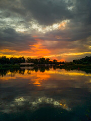 Obraz premium Cloudy sunset reflecting in Odra river