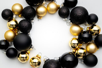 Noel background. Black baubles, golden balls in Christmas decoration on white background for greeting card. Flat lay, top view, copy space.