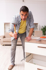 Young male carpenter repairing furniture at home